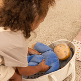 Child putting a cloud nana Kathe Kruse waldorf doll in a carry basket.