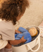 Child putting a cloud nana Kathe Kruse waldorf doll in a carry basket.