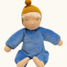 Kathe Kruse cloud nana waldorf doll showing a blue outfit and mustard yellow knitted hat, light skin and hair