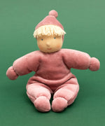 Kathe Kruse Lolo Rose waldorf doll showing a light pink towelling outfit, sitting in front o a green background