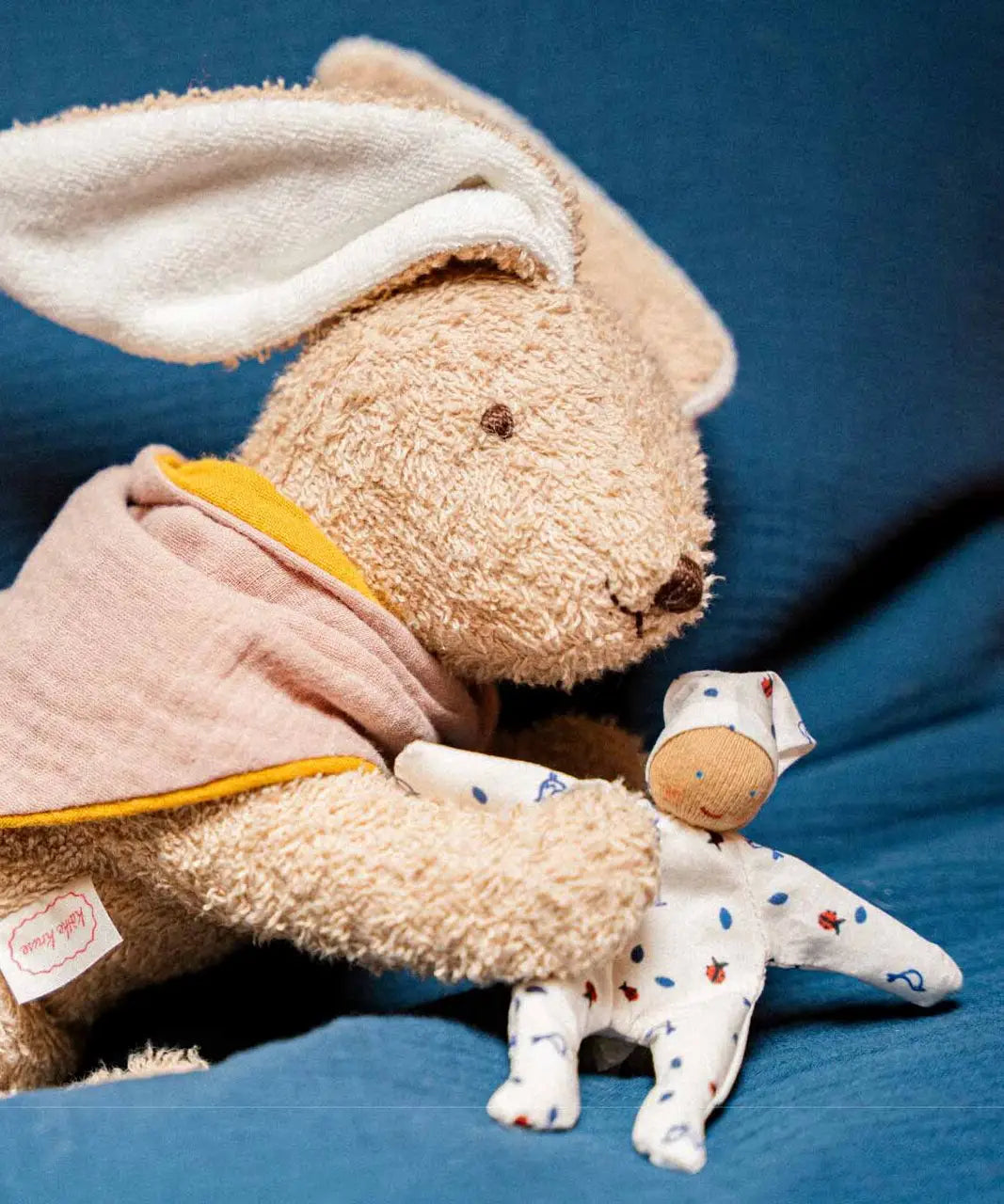 Kathe Kruse holly lying rabbit comforter holding a small white waldorf doll 
