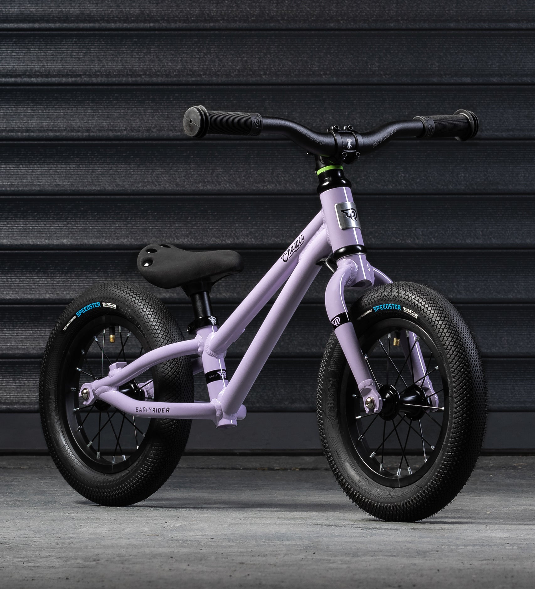 A closer look at the Early Rider Charger Balance Bike - Violet Haze from the front and side, on a grey background