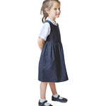 A little girl wearing the Eco Outfitters organic and fair trade cotton school pinafore dress in navy.