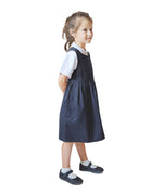 A little girl wearing the Eco Outfitters organic and fair trade cotton school pinafore dress in navy.