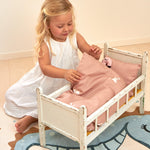 A child playing with a Roommate teddy inside a dolls bed, with the Roommate Doll Bedding Set - Rabbit