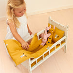 A child playing with a small dolls bed, with the Roommate Doll Bedding Set - Tiger inside