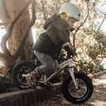 A child going down a raised brick boarder of a path, showing how robust the Early Rider Big Foot Balance Bikes are, and that they can be used on different terrains.