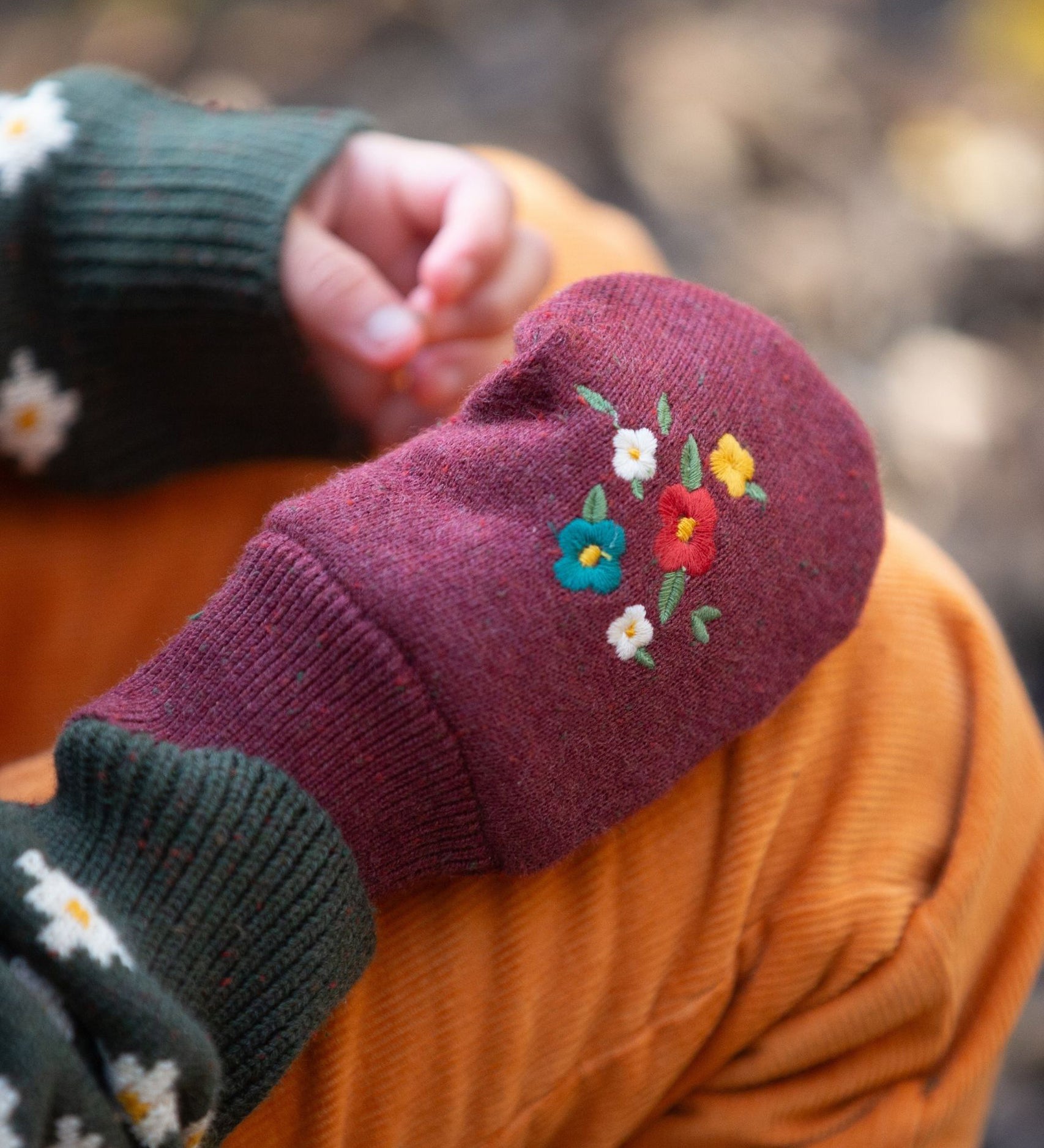 A closer look at the knitted gloves featuring a beautiful embroidered flower design on the back of the hand