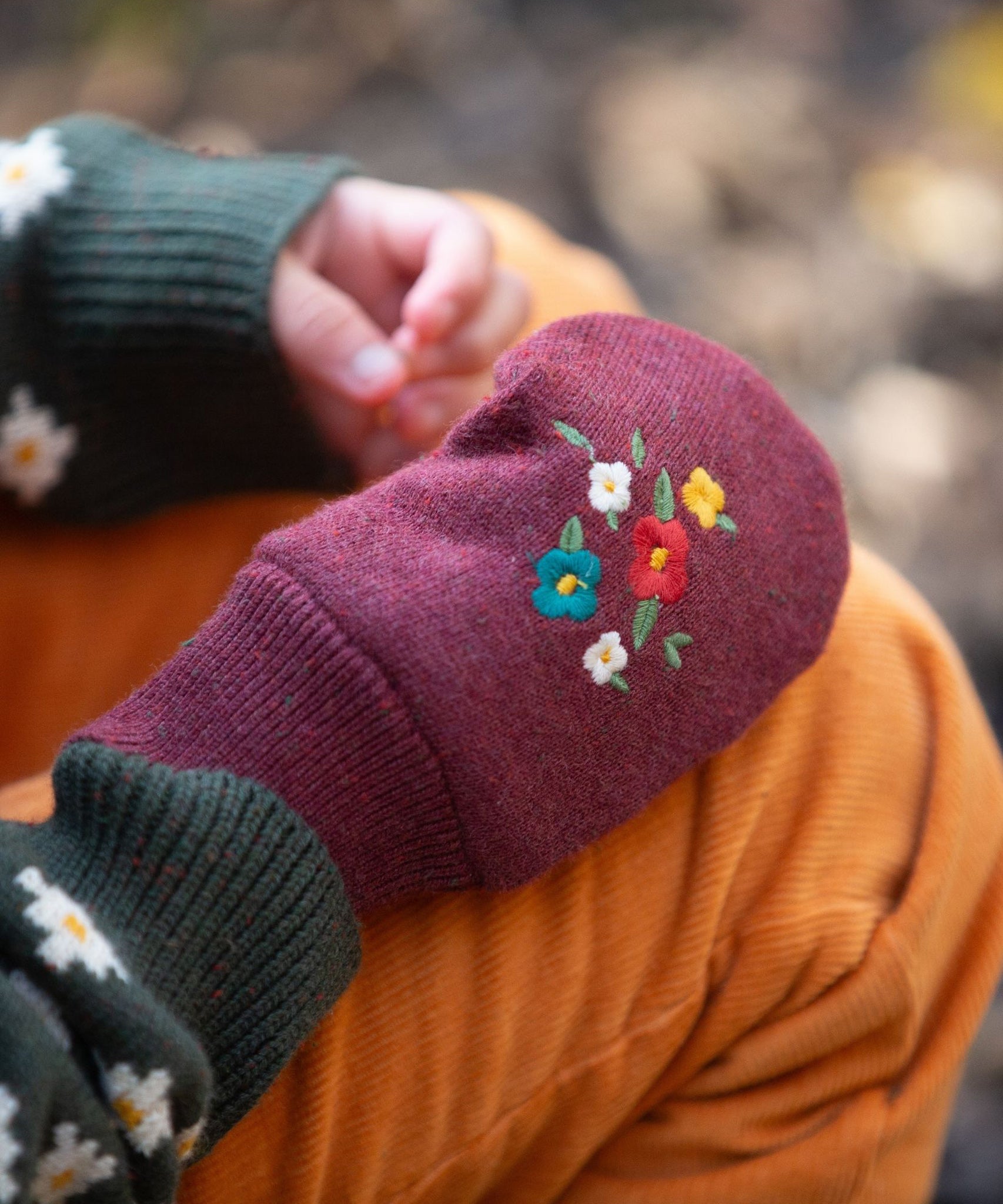 A closer look at the knitted gloves featuring a beautiful embroidered flower design on the back of the hand