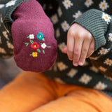 A child wearing one of the Hazelnut mittens, and one hand without to show the size of the glove on the hand