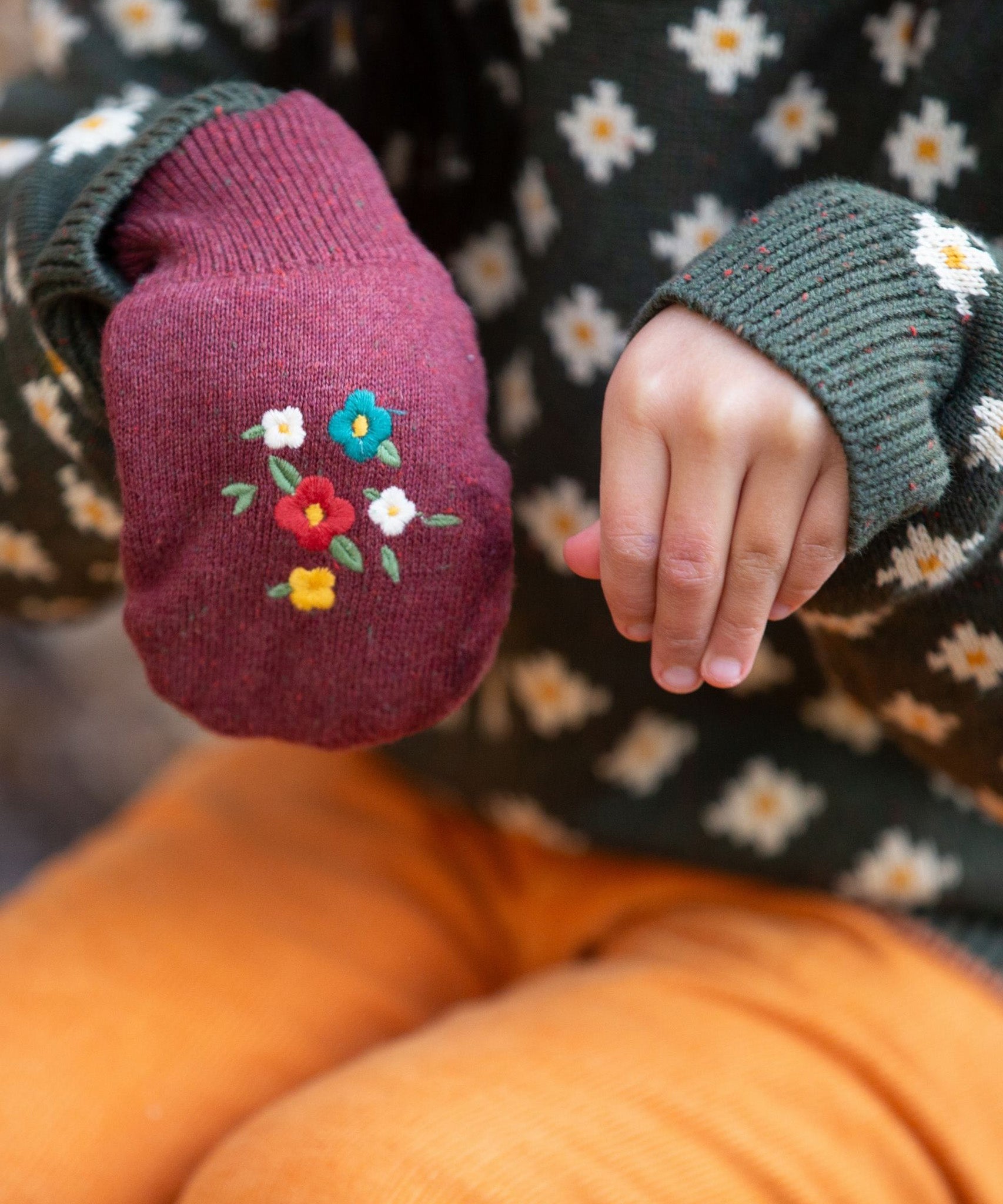 A child wearing one of the Hazelnut mittens, and one hand without to show the size of the glove on the hand