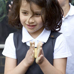 A little girl wearing the Eco Outfitters organic and fair trade cotton school pinafore dress in grey.