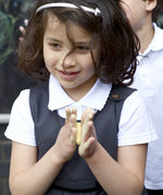 A little girl wearing the Eco Outfitters organic and fair trade cotton school pinafore dress in grey.