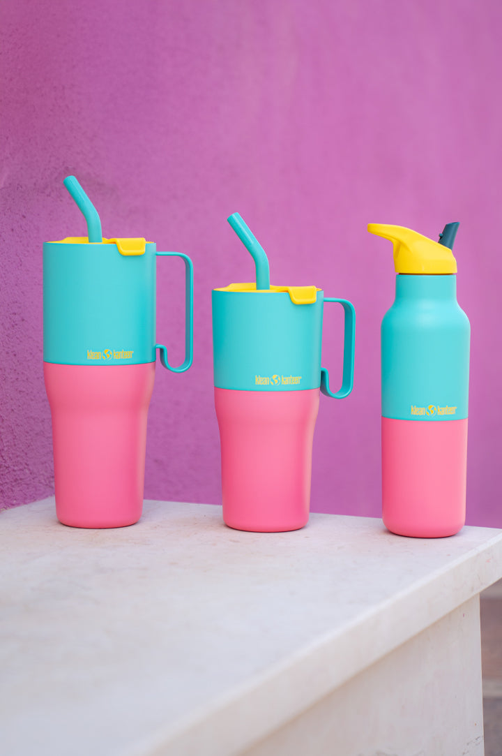 Two Klean Kanteen Rise Tumblers and one classic bottle in matching pink, turquoise and yellow - bright on a shelf with pink wall behind to represent the brand at Babipur, UK supplier of the whole range! 