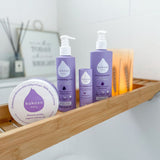Kokoso softly coconut scented organic baby range standing on a wooden plate above a bath including the soft balm, body wash and coconut oil all available at Babipur.