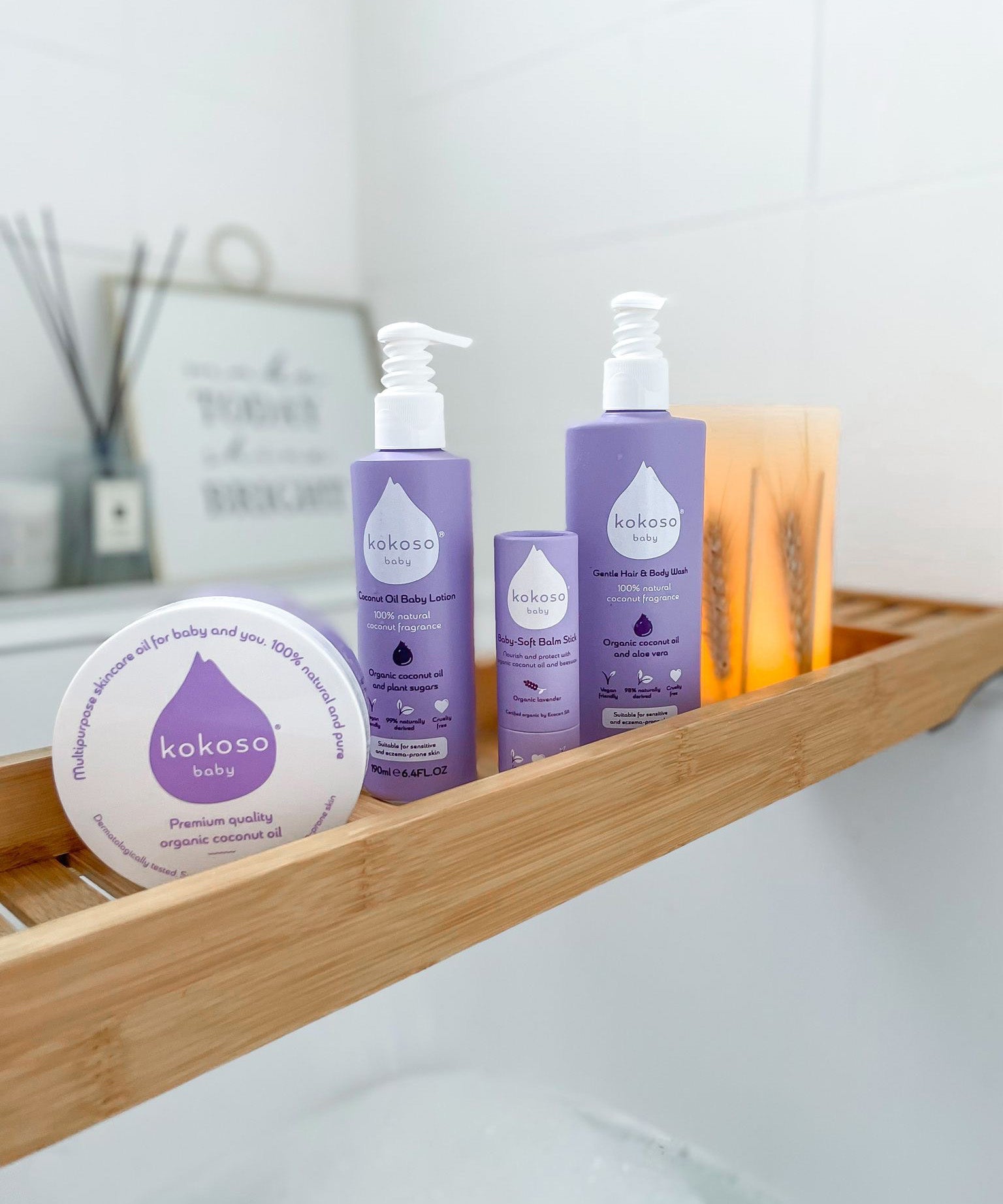 Kokoso softly coconut scented organic baby range standing on a wooden plate above a bath including the soft balm, body wash and coconut oil all available at Babipur.