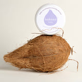 Kokoso baby organic coconut oil tub standing on a whole coconut. Tub available at Babipur 