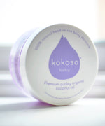 A close up of a Kokoso baby organic coconut oil tub on it's side showing the branding on the white lid. Tub available at Babipur.