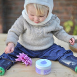 A baby sitting on a wooden surface with the Kokoso baby organic coconut oil, tub available at Babipur. 