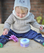 A baby sitting on a wooden surface with the Kokoso baby organic coconut oil, tub available at Babipur. 
