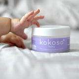 A close up of a baby's hand touching the Kokoso baby organic coconut oil, tub available at Babipur. 