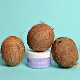 Kokoso 70g baby organic coconut oil standing next to 3 whole coconuts. Tub available at Babipur.