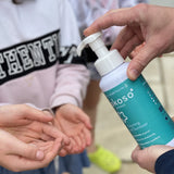 A close up of an adult hand dispensing the Kokoso protect foaming hand sanitiser from the 500ml bottle available at Babipur.