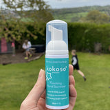A close up of an adult hand holding the Kokoso protect foaming hand sanitiser  50ml bottle available at Babipur showing the size of the bottle 