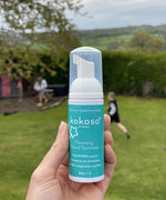 A close up of an adult hand holding the Kokoso protect foaming hand sanitiser  50ml bottle available at Babipur showing the size of the bottle 