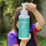 A child standing in a garden and holding the Kokoso protect foaming hand sanitiser original 500ml bottle available at Babipur.