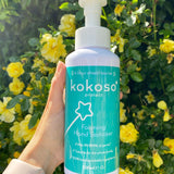 A close up of an adult hand holding the Kokoso protect foaming hand sanitiser  500ml bottle available at Babipur showing the size of the bottle 