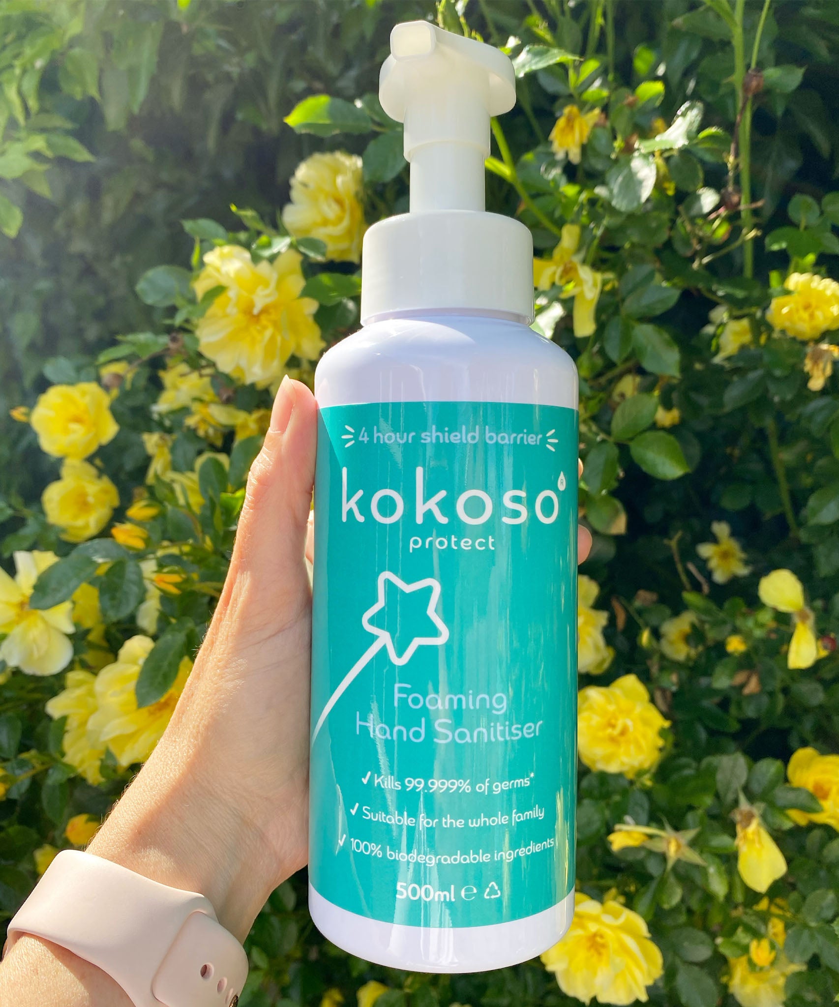 A close up of an adult hand holding the Kokoso protect foaming hand sanitiser  500ml bottle available at Babipur showing the size of the bottle 