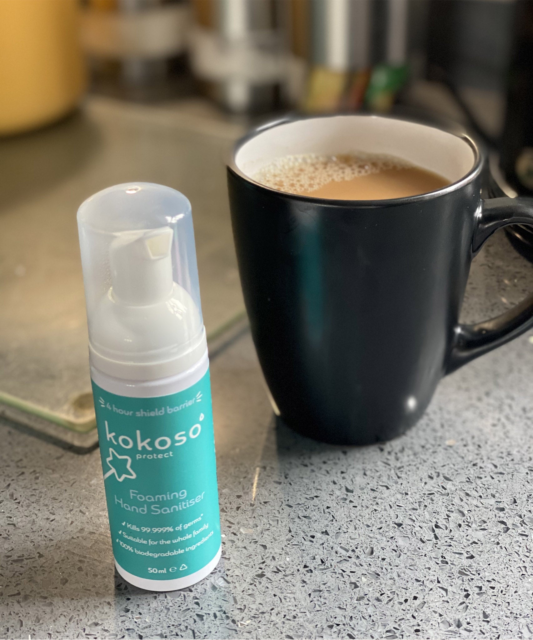 Kokoso protect foaming hand sanitiser original 50ml bottle standing next to mug of tea. Bottle available at Babipur.