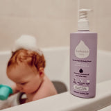 Kokoso softly coconut scented organic baby body and hair wash 200ml bottle standing on the side of the bath with a baby inside. 