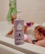 Kokoso softly coconut scented organic baby body and hair wash 200ml bottle standing on the side of the bath with a baby inside. Bottle Available at Babipur.