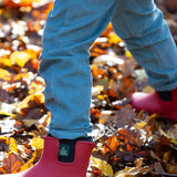 A child playing on wet leaves and wearing the Little Green Radicals natural rubber ankle wellington boots