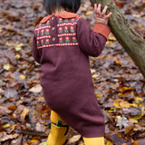 A close up of a child wearing the dark maroon Little Green Radicals collecting flowers knitted collar dress showing the button fastener and the retro flower design detail.