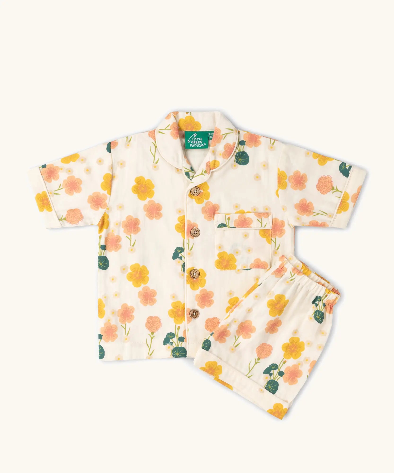 Little Green Radicals organic cotton children's short pyjamas set in cream with a pink and yellow flora print. 
