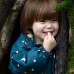 A child happily playing in the woods, wearing the LGR Starry Night Waterproof Winter Suit and showing the elasticated wrist band