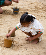A child making sand castles, whilst wearing the LGR Adventure Hooded Beach Towel Poncho
