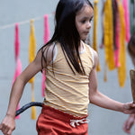 A child wearing the yellow stripe vest top, from the LGR Adventure Organic Vest Set - 3 Pack