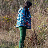 Child wearing a Little Green Radicals blue sun birds recycled waterproof adventure Winter coat with green trousers.