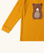 Close up of the front of the Little Green Radicals gold bear applique organic cotton long sleeve childrens top.