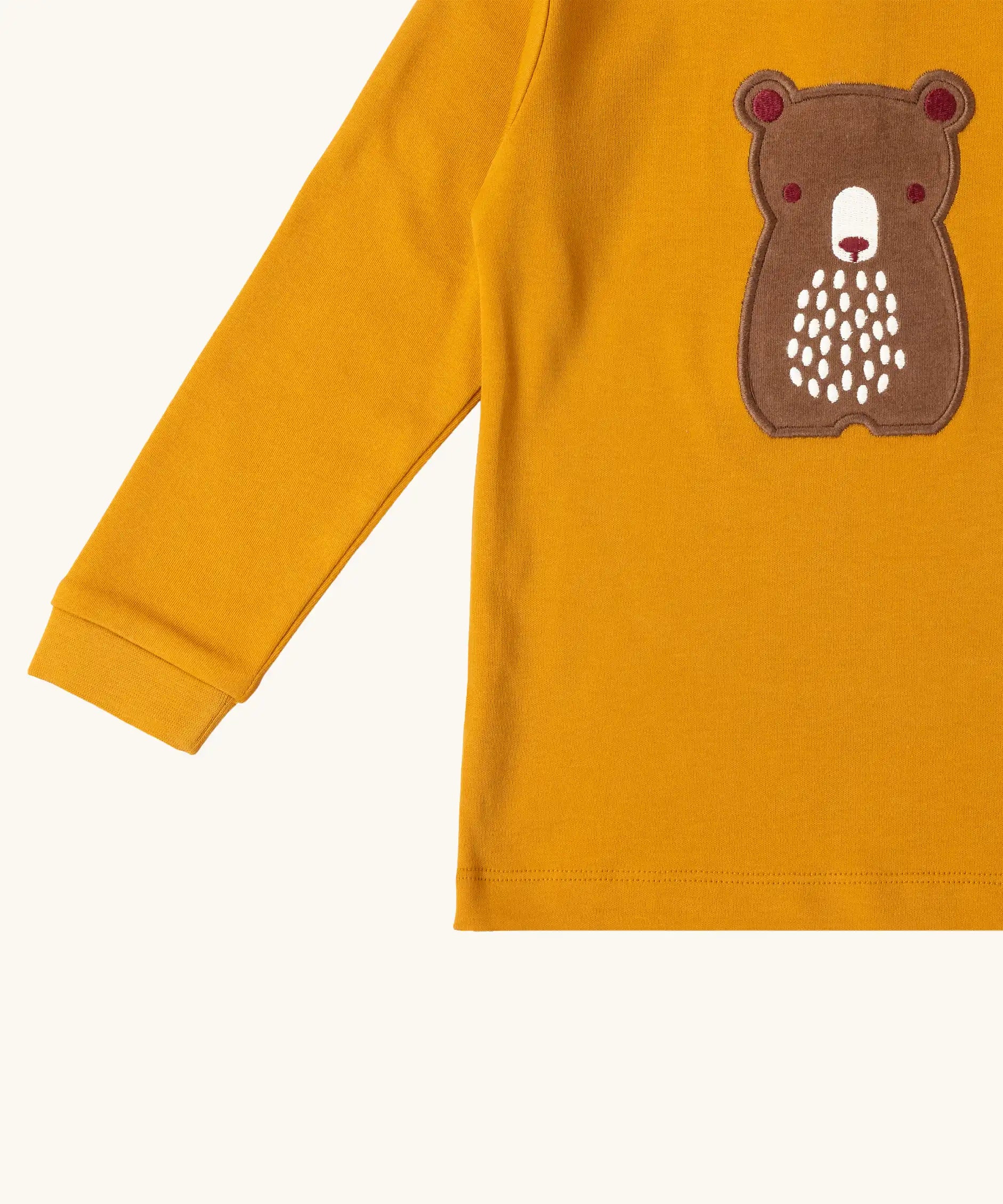 Close up of the front of the Little Green Radicals gold bear applique organic cotton long sleeve childrens top.