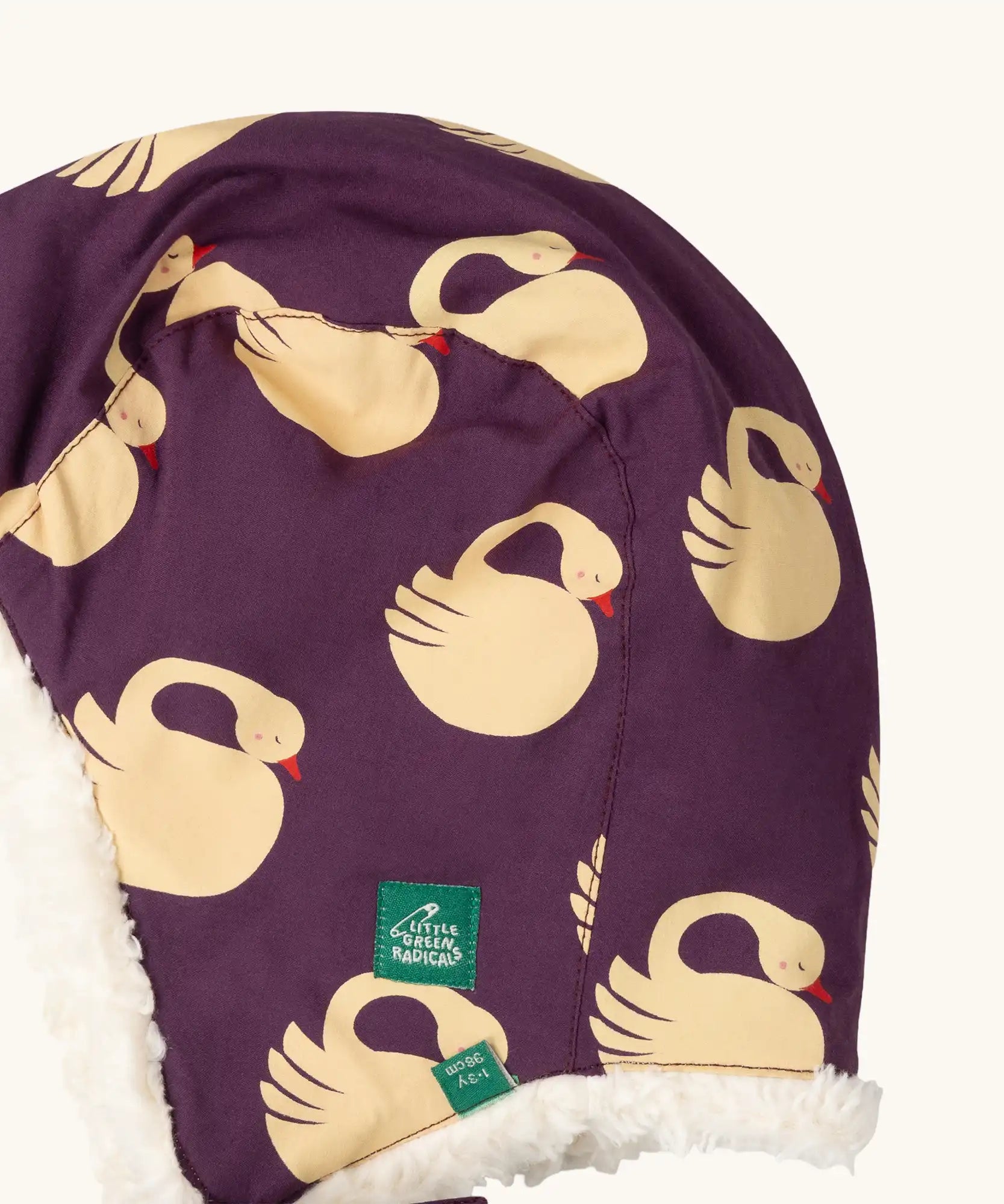 Close up of Little Green Radicals  sleeping swans print sherpa fleece lined purple hat. Purple organic cotton sherpa fleece lined flapper style hat with a sleeping swans print. 