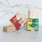 The Lamazuna Solid Face Scrub Bar and the Nourishing Lamazuna Dream Cream bar with their colourful packaging, on a white and grey marbled background