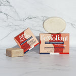 The Lamazuna Solid Face Scrub Bar and the Lamazuna Exfoliating Body Scrub Bar next to each other with their packaging boxes, on a white and grey marbled background