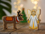 Lanka Kade Christmas angel toy with yellow and white dress, wings and halo next to a Lanka Kade reindeer with Christmas reins and seat.