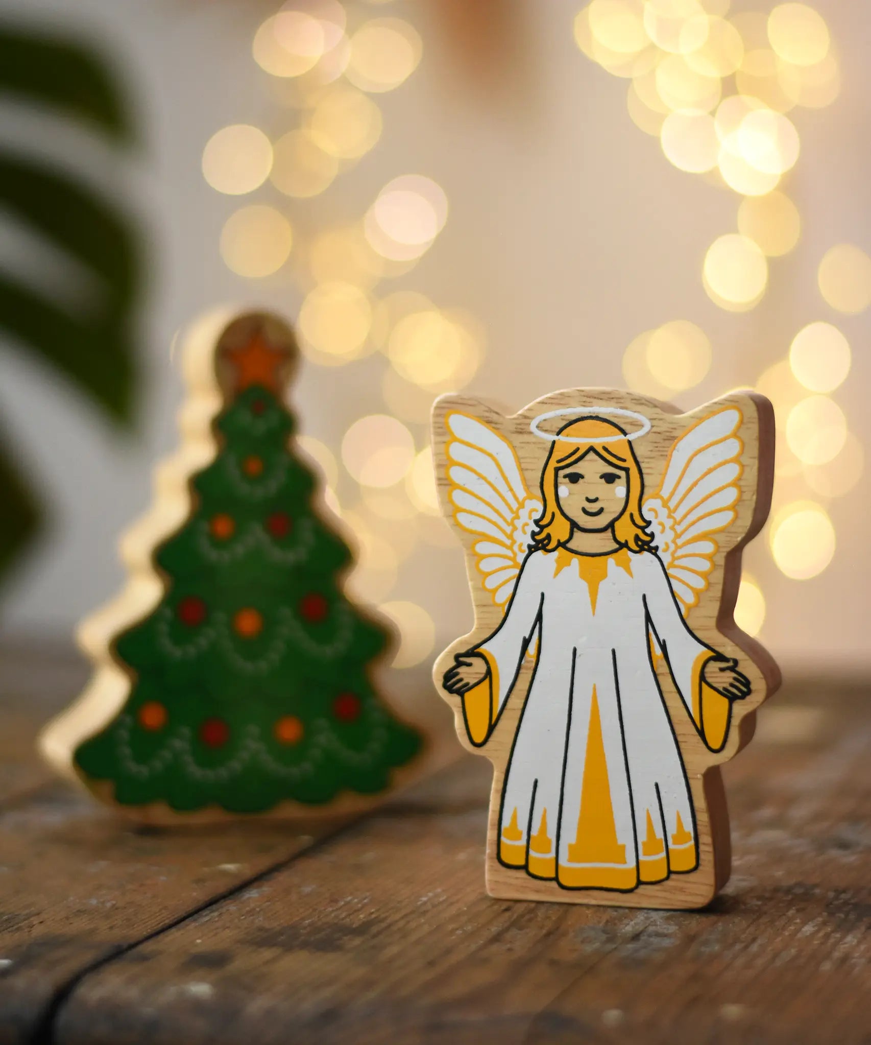 Lanka Kade Christmas angel toy, a wooden figure printed on both sides, next to a Lanka Kade Christmas tree.