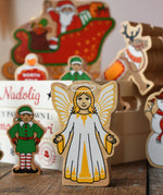 Lanka Kade Christmas angel toy in yellow and white next to a Christmas eve box filled with Lanka Kade figures.